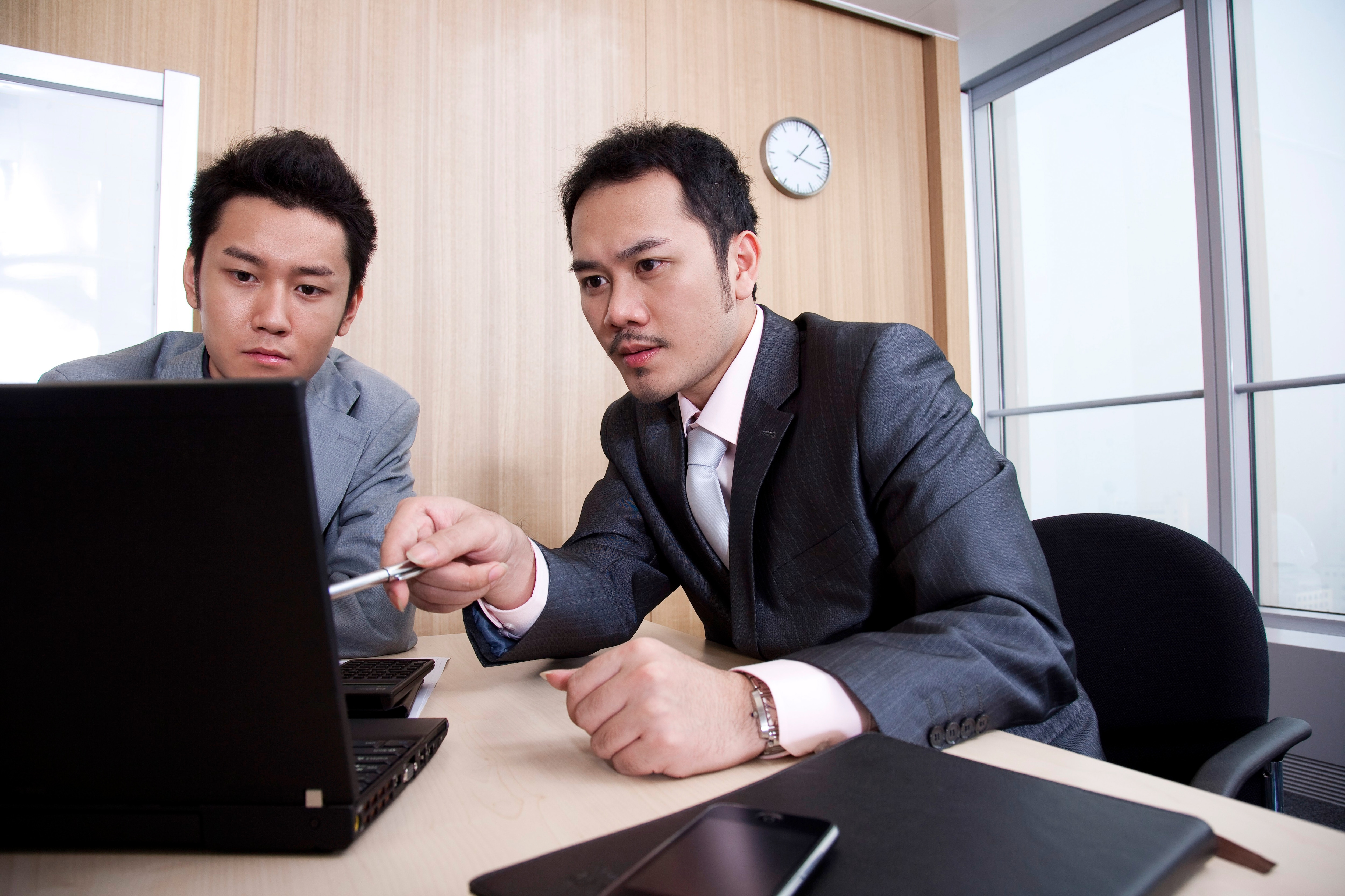 Two men looking at a computer and talking