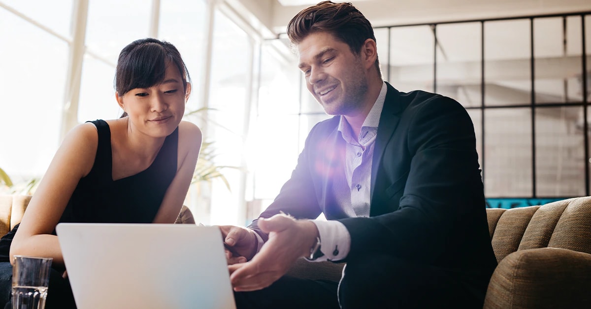 Man and woman conversing while looking at a laptop