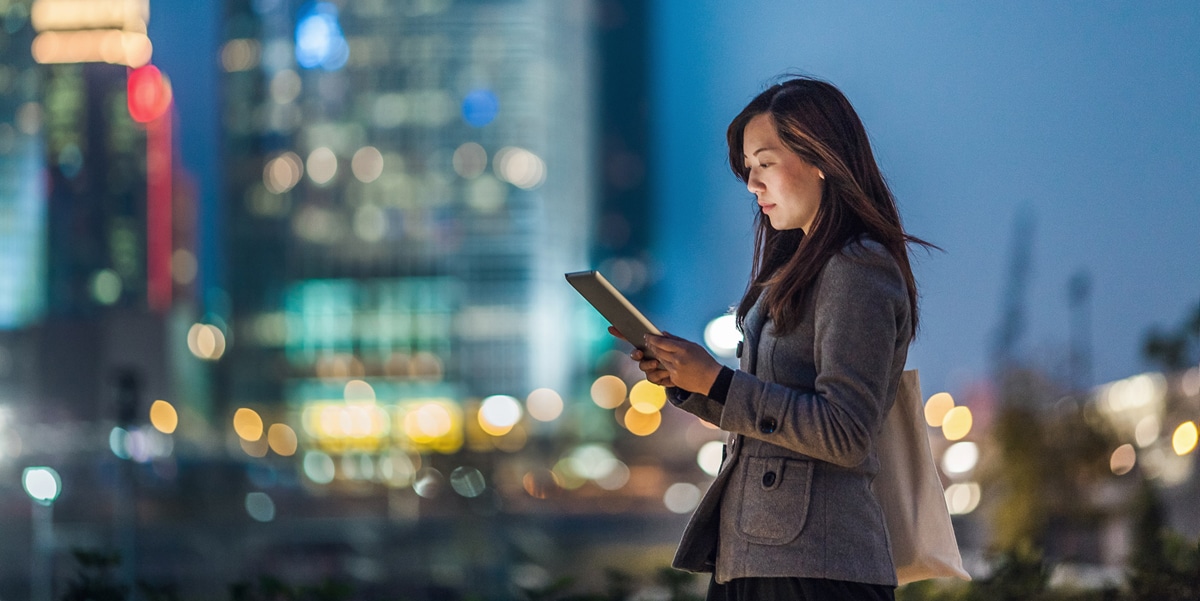 Woman with dark hair standing outside holding a tablet