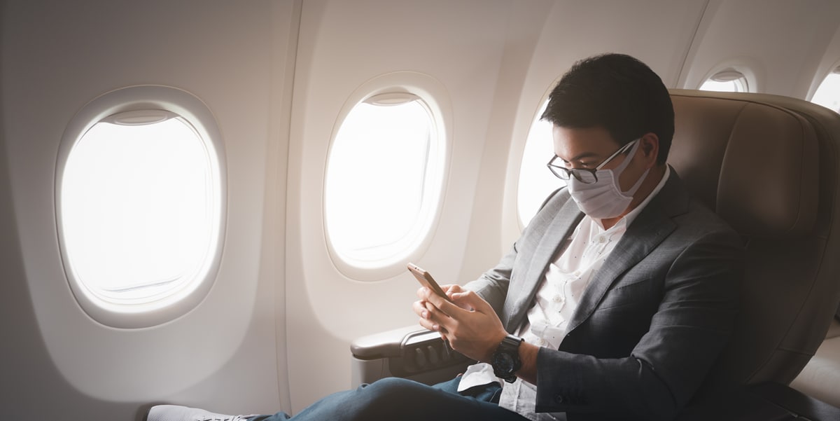 Man sitting on an airplane looking at his phone