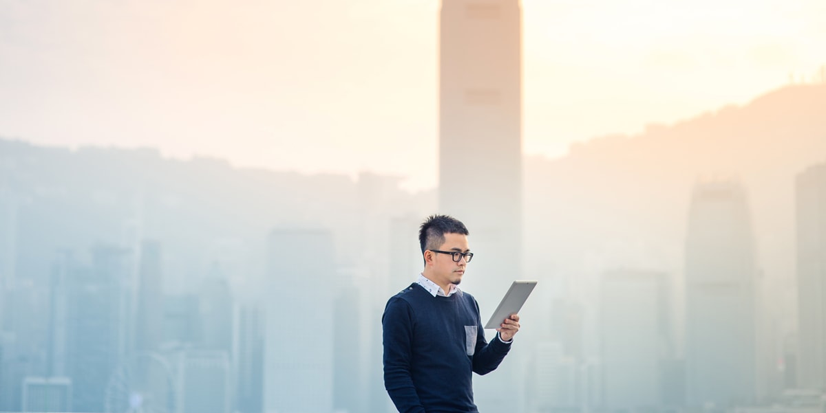 man with glasses holding tablet outside