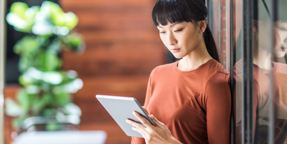 Woman in a red shirt holding a tablet she is looking at